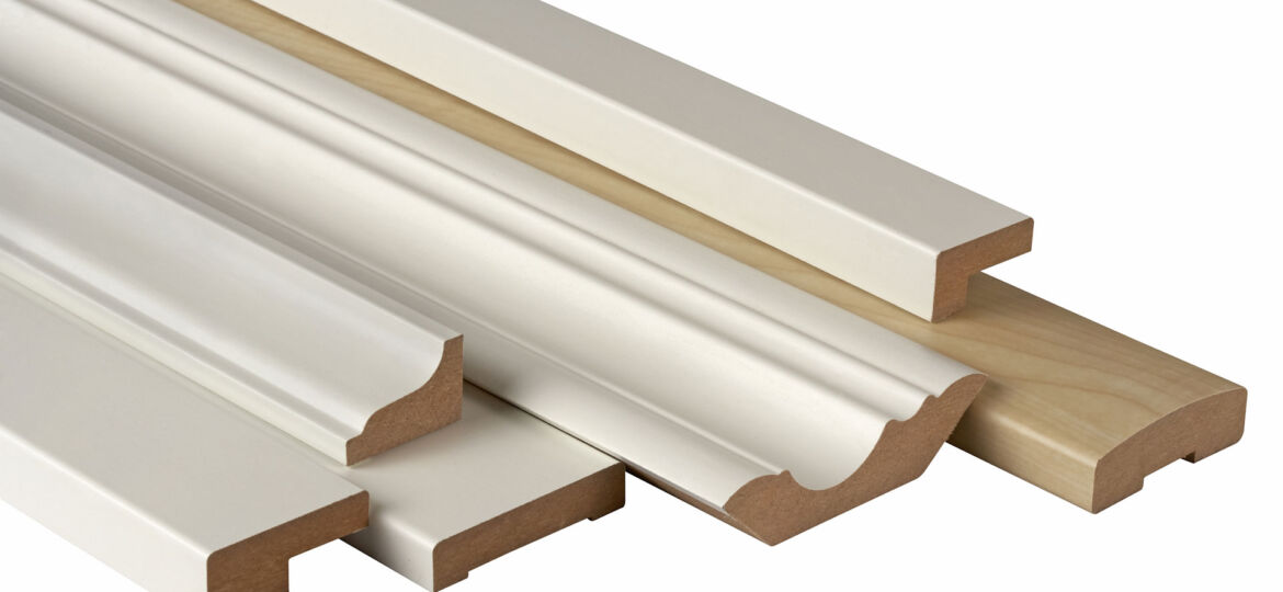 An assortment of wooden moldings ore baseboards with various profiles, painted white, displayed against a white background, typically used for trimming or framing in construction and interior design.