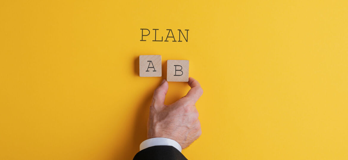 A person in a business suit holding two cardboard letters 'A' and 'B' against a yellow background with the word 'PLAN' above, symbolizing strategic planning and decision making between two options such as traditional flooring and epoxy flooring.