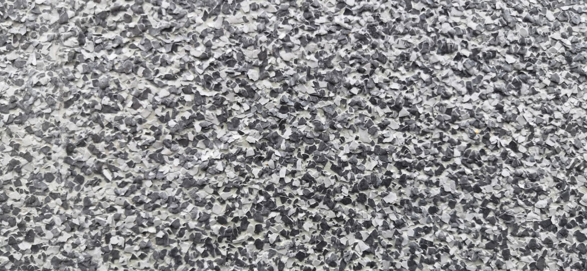 Close-up of a granulated surface with a speckled pattern, primarily in shades of gray, resembling a texture that might be used for grip or anti-slip purposes.