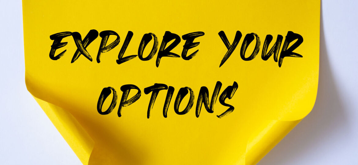 The phrase 'EXPLORE YOUR OPTIONS' handwritten in bold black ink on a curled yellow sticky note, symbolizing the idea of considering various possibilities or opportunities such as epoxy texture, color, thickness, and sealers.