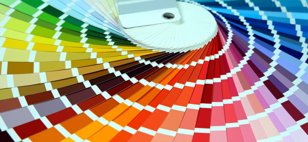An expansive color swatch fan spread out to display a gradient of colors ranging from greens, yellows, and browns to oranges, reds, pinks, and blues. Each swatch is marked with a square indicating the specific shade, providing a comprehensive palette for design and color selection purposes.